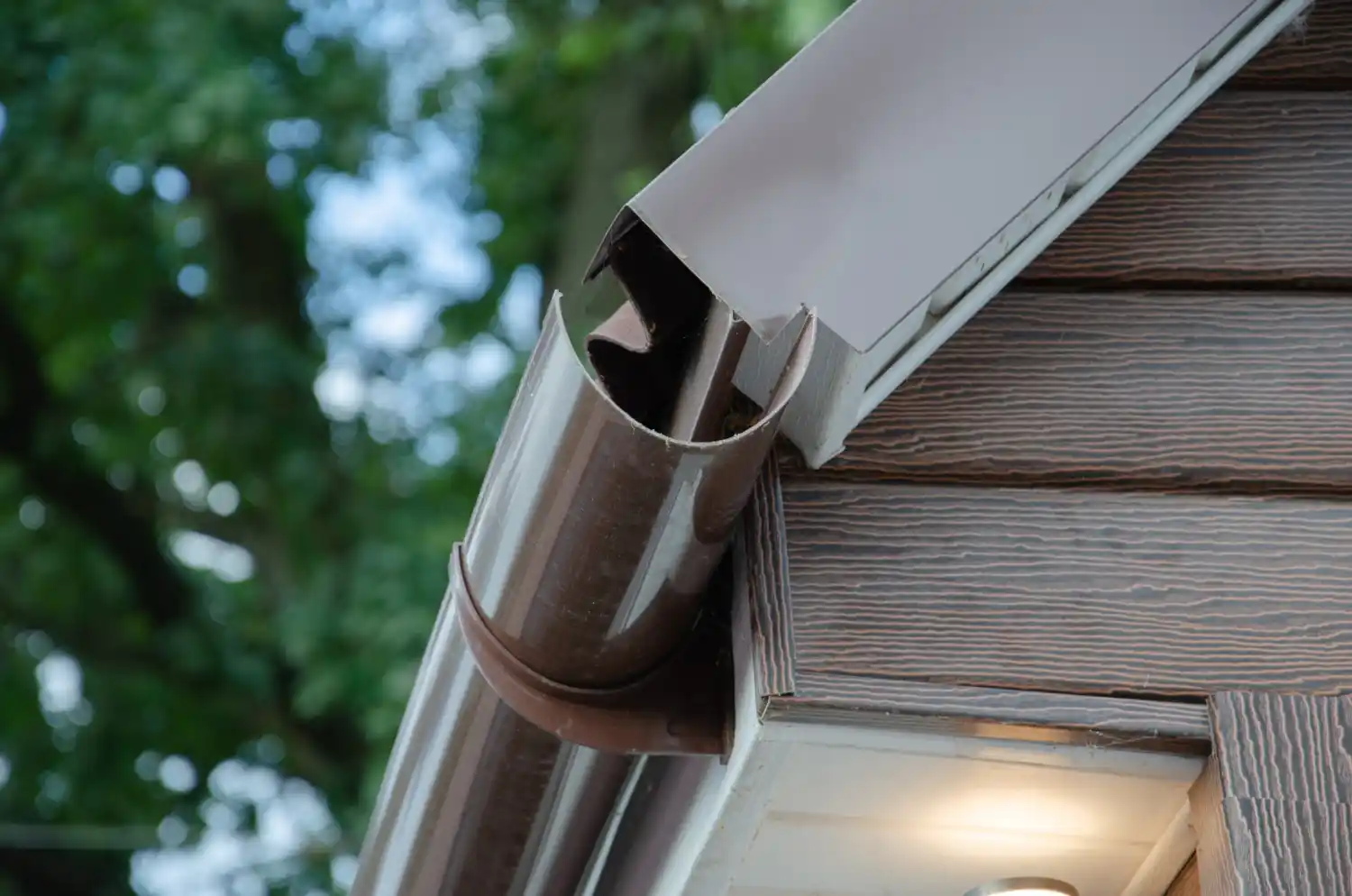 Technician sealing leaking gutter to prevent water damage to home