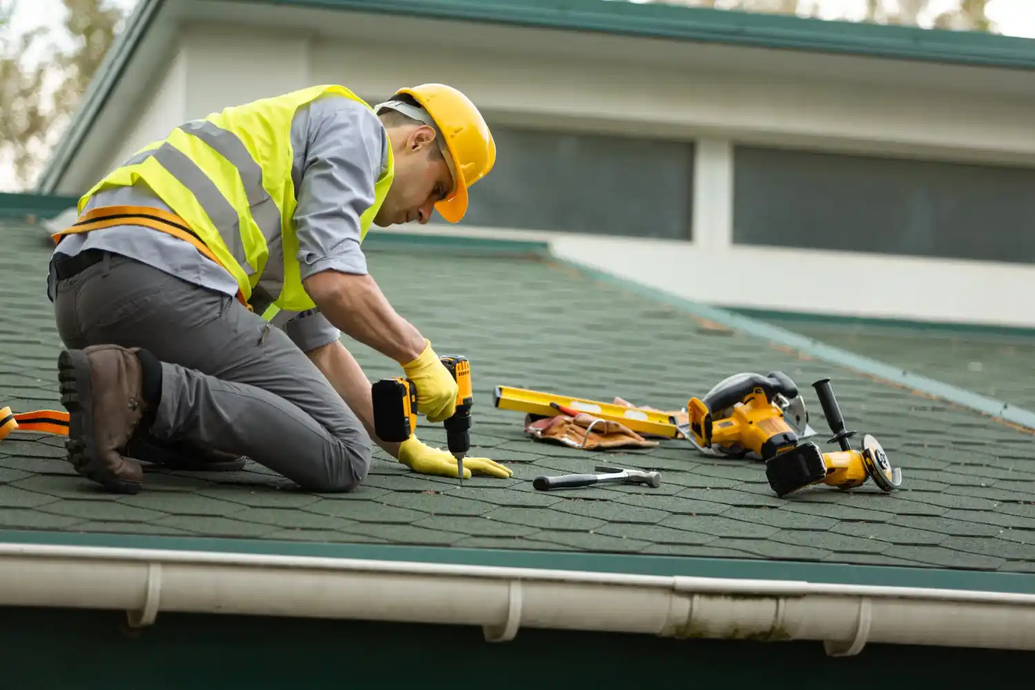 Technician cleaning roof gutters before installing gutter guards